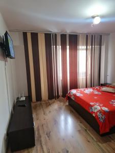 Schlafzimmer mit einem roten Bett und einem TV in der Unterkunft Apartament Ireg in Galaţi