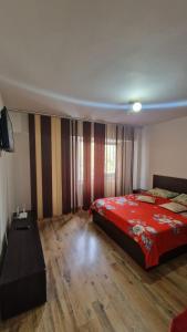 Schlafzimmer mit einem roten Bett und einem TV in der Unterkunft Apartament Ireg in Galaţi
