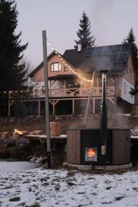 a house with a stove in front of it in the snow at Mountain Air Lodge in Izvoru Mureşului