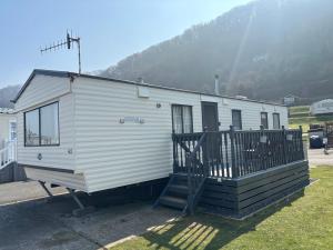 a white trailer parked in a field with a mountain at Ocean Breeze Hideaway 2 Bed Pet Friendly Static Caravan In Clarach Bay in Aberystwyth