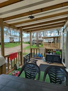 a covered patio with chairs and a grill at MOBIL - HOME 2 6p Bois de Bayadene in Piriac-sur-Mer