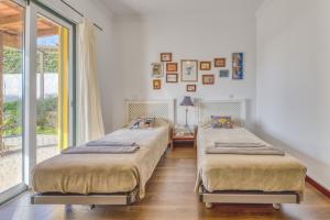 twee bedden in een kamer met een raam bij Casa Alto de Santo Antonio in São Brás de Alportel