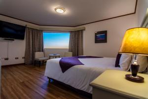 a hotel room with a bed and a large window at Edenia Hotel & Nature in El Calafate