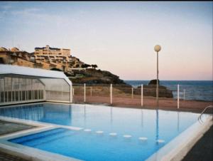 a swimming pool in front of a building and the ocean at Entrecalas Cabo de Palos in Cabo de Palos