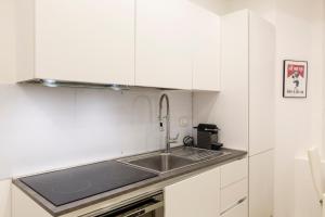 een keuken met witte kasten en een spoelbak bij Campus Bligny - Bocconi District in Milaan