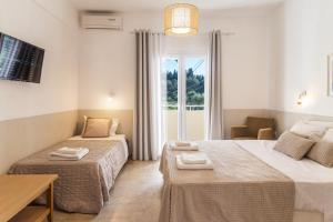 a hotel room with two beds and a window at BOHOTEL Eleonas Anex Apartments in Kavos