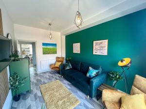 a living room with a couch and a green wall at Modern Two Bed House With EV Off Road Parking in Henwick