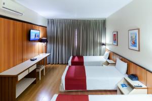 サンパウロにあるホテル パン アメリカーノのベッドと机があるホテルの部屋