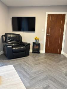 a black leather chair in a living room with a flat screen tv at The Drey in Poole
