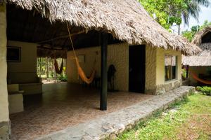 a house with a thatched roof with a hammock outside at Taironaka Eco Hotel in Don Diego