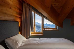 a bed in a room with a large window at La Tana Lodge & SPA in La Colla
