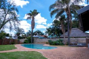 a swimming pool in a yard with palm trees at Flora Haven in Polokwane
