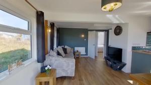 a living room with a couch and a tv at G17 St Meva, Riviere Towans in Hayle