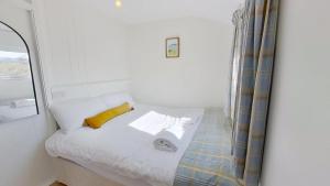 a bedroom with a bed with a yellow pillow and a mirror at G17 St Meva, Riviere Towans in Hayle