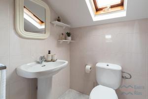 a bathroom with a sink and a toilet and a mirror at Casa de Pili - by entreRías in Cangas de Morrazo +8 photos