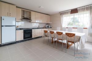 a kitchen with a table and chairs and a refrigerator at Casa de Pili - by entreRías in Cangas de Morrazo
