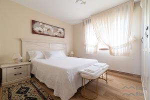 a white bedroom with a bed and a stool at Casa de Pili - by entreRías in Cangas de Morrazo