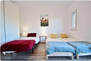 two beds in a room with white walls at Bright by the Beach - by CoH in Cruz Quebrada
