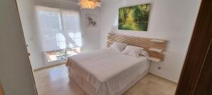 biała sypialnia z łóżkiem i oknem w obiekcie Mijas Golf penthouse w mieście Santa Fe de los Boliches