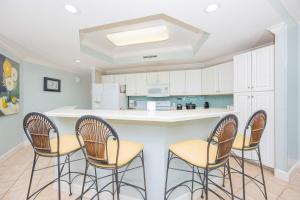 a kitchen with four chairs around a kitchen island at Phoenix on the Bay 1427 condo in Orange Beach