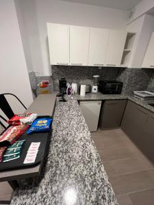 a kitchen with white cabinets and a granite counter top at Studio con amenities zona Hospital Italiamo 6 in Buenos Aires +2 photos