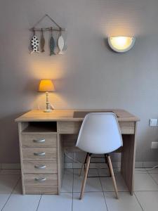 a desk with a white chair and a lamp at Appart-Hotel des coquillages Résidence Kiwi in Aytré