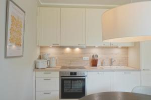 a kitchen with white cabinets and a stove top oven at Charmante TOP Ferienwohnung Wippsteert auf Rügen, großer Garten und Sonnen Terrasse am Golf Platz und Nationalpark Jasmund in Lohme