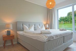 a bedroom with a large bed with a large window at Charmante TOP Ferienwohnung Wippsteert auf Rügen, großer Garten und Sonnen Terrasse am Golf Platz und Nationalpark Jasmund in Lohme +17 photos