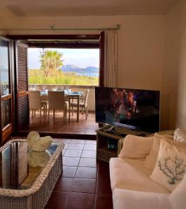 a living room with a couch and a tv and a table at Over The Sea Punta Lada in Porto Rotondo