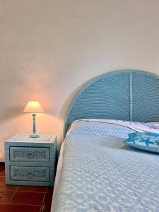 a bed with a blue headboard and a lamp on a night stand at Over The Sea Punta Lada in Porto Rotondo +30 photos