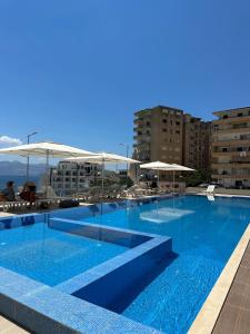 Una gran piscina azul con sillas y sombrillas. en J&P Apartments Saranda, en Sarandë