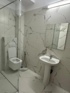 Un baño blanco con lavabo e inodoro. en J&P Apartments Saranda, en Sarandë