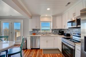 une cuisine avec des armoires blanches et une table dans l'établissement Sea Biscuit, à Surf City