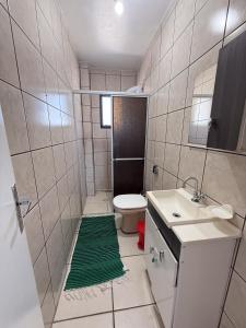 El baño incluye ducha, aseo y alfombra verde. en Residencial Santinho, en Florianópolis 15 fotos más