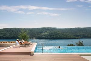 a woman sitting in a chair next to a swimming pool at Villa Vlastelini 2 in Labin