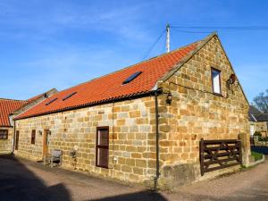 Un viejo edificio de ladrillo con techo rojo en The Old Dairy, Ellerby, en Saltburn-by-the-Sea