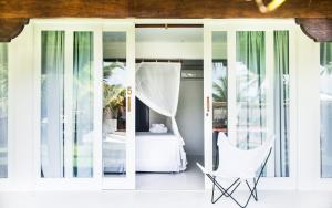 um quarto com uma cama e uma cadeira branca em Pousada Brisas do Espelho em Praia do Espelho