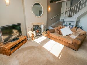 een woonkamer met een bank en een televisie bij Kirk Yett Cottage in Skipton