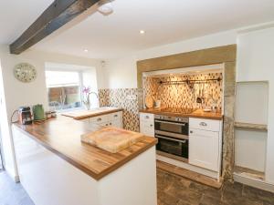 een keuken met witte kasten en een houten aanrechtblad bij Kirk Yett Cottage in Skipton