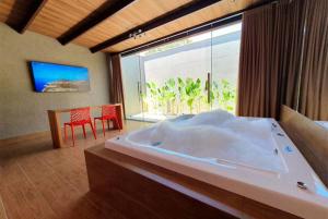 a bedroom with a large bed and a large window at Jardins Suites in Conselheiro Lafaiete