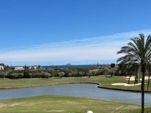 a golf course with a pond and palm trees at Casa Matthis in Los Alcázares