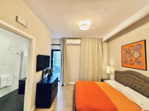 a bedroom with an orange bed and a television at Les Suites Bari Italian Excellence Bed and Breakfast in Bari