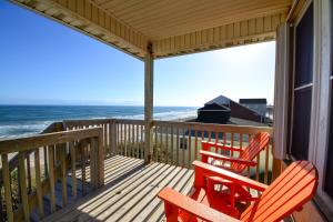 twee rode stoelen op een veranda met uitzicht op de oceaan bij Oakley's Oasis in Surf City