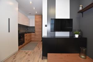 a kitchen with black cabinets and a flat screen tv at Apartamenty K netflix wi-fi gratis in Wałbrzych +30 photos