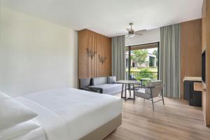 a hotel room with a bed and a couch and a table at Jim Corbett Marriott Resort & Spa in Rāmnagar +17 photos