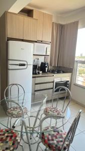cocina con mesa de cristal con sillas y nevera en Refúgio Urbano - central c garagem, en Santa Maria 2 fotos más