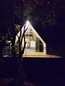 a house with a deck at night with a tree at Nirved Retreat Resort - A Backwater Forest Peaceful Stay in Bhor, Pune in Āpti