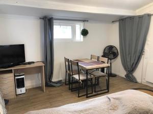 a room with a table and chairs and a television at Chez Emma in Beauchamp