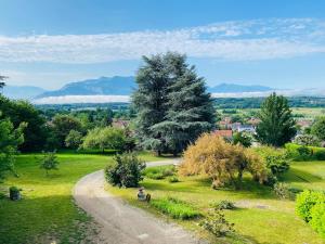 a dirt road through a field with trees and mountains at Nature loft, calme et confortable in La Murette