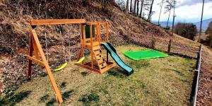 a playground with a swing set on a hill at Lil Cabin in the Cove! MTN views, theater, hot tub, games, king beds, Prime Location! in Sevierville